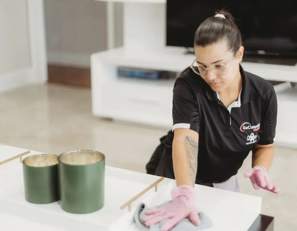 Go Cleaning Maids professional performing Airbnb cleaning in a living room with modern decor