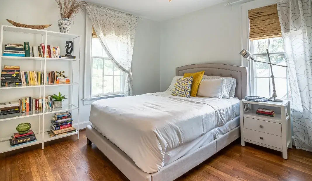 Clean and organized bedroom with natural light and neatly arranged bedding