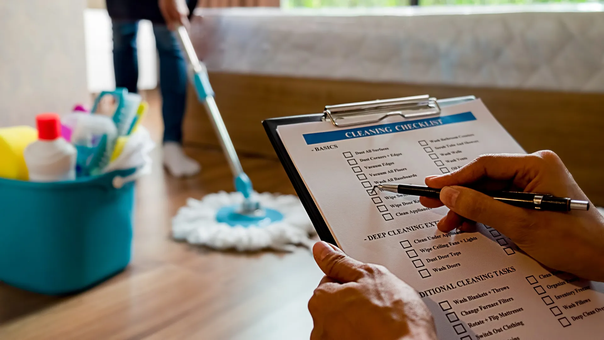 Person reviewing a room by room cleaning checklist while cleaning a home.